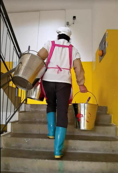 9、提着三个桶正在派送餐具的食堂阿姨.png